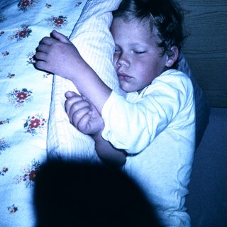 Child peacefully sleeping in bed at night.