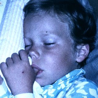Child peacefully sleeping in blue floral pajamas.