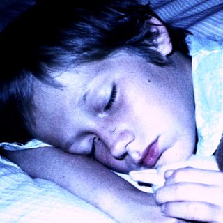 A child sleeping peacefully with a stuffed toy.