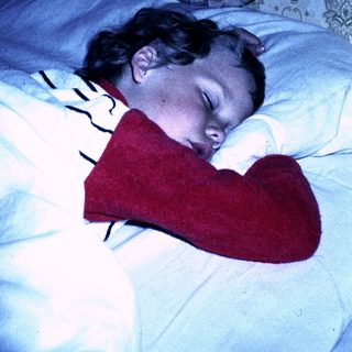 A child sleeping peacefully with a stuffed heart-shaped toy.