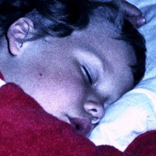 A child sleeping peacefully with a stuffed heart-shaped toy.