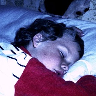 A child sleeping peacefully with a stuffed heart-shaped toy.