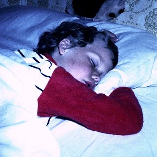 A child sleeping peacefully with a stuffed heart-shaped toy.