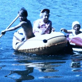 People paddling in an inflatable boat on calm water.