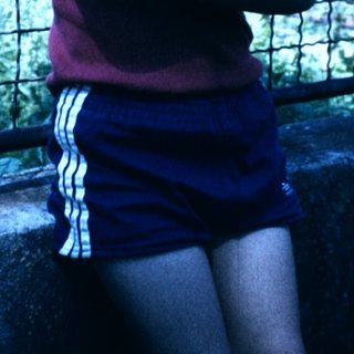 Boy hugging a cat near a fence.