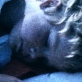 Child resting on blanket in natural setting.