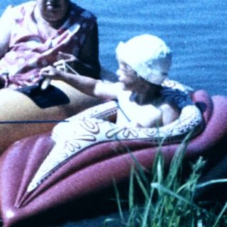 Family enjoying inflatable boat ride on calm lake.
