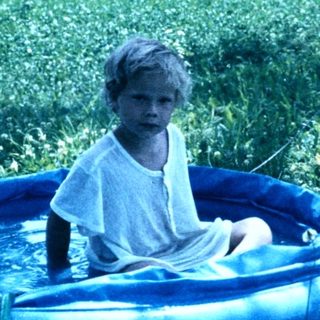 Child sitting in inflatable pool outdoors.