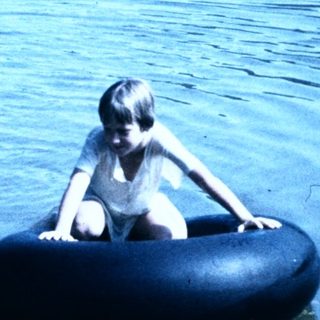 Two children playing in water with inflatable tubes.