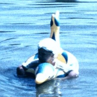 Person swimming in water with floating tire.