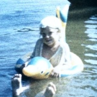 Person sitting in water with large tire.
