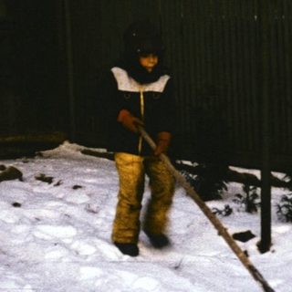 Person shoveling snow in residential area at night.