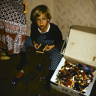 Child playing with open LEGO brick box.
