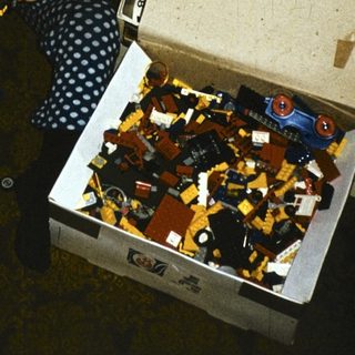 Child playing with open LEGO brick box.