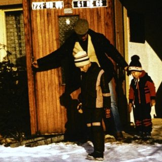 People shoveling snow outside a house at night.