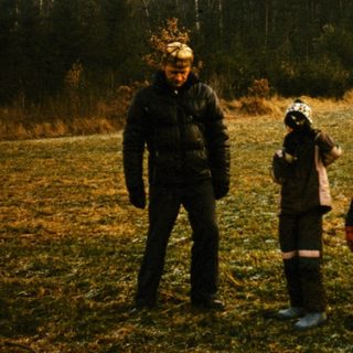 Three people in traditional winter clothing standing outdoors.