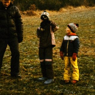 Three people in traditional winter clothing standing outdoors.