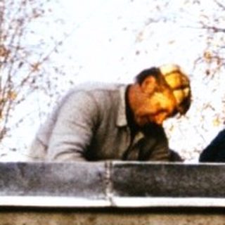 Two people repairing rustic roof on old building.