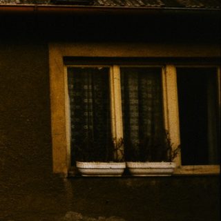 Two people repairing rustic roof on old building.