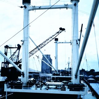 Large ship with tall cranes docked at port.