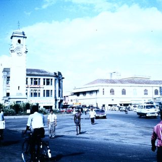 Busy urban street scene with clock tower building.