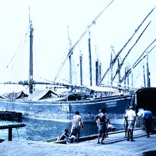 Historic sailing ship docked at port with crew.