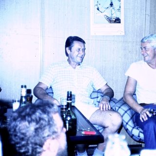 Three adults laughing together indoors during a social gathering.