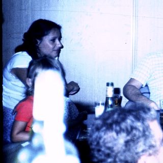 Three adults laughing together indoors during a social gathering.