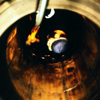 Glassblowing molten glass in furnace.