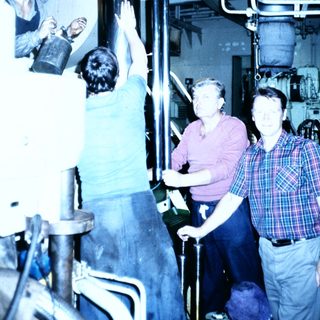 Industrial facility workers inspecting large cylindrical tanks.