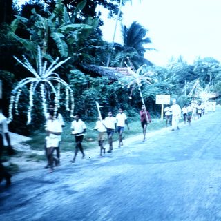 Group of people marching in rural road procession.