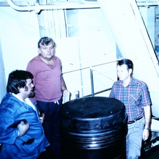 Scientists inspecting large industrial equipment in lab.