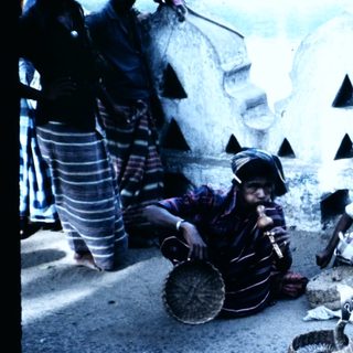 Three men sitting on ground sorting grains.