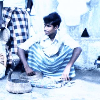 People preparing traditional food outdoors using clay pots.