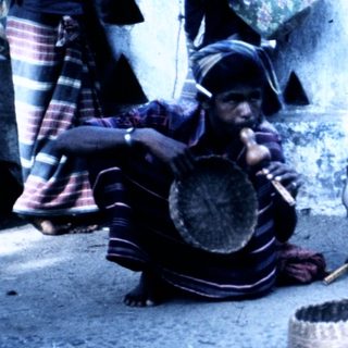 People preparing traditional food outdoors using clay pots.
