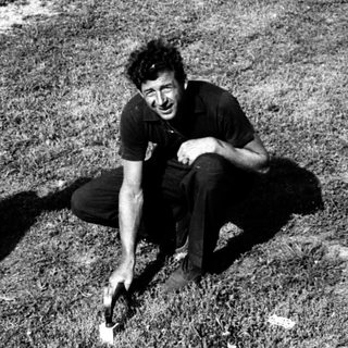 Man kneeling outdoors, holding a small object.