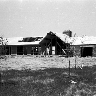 Mid-century modern house under construction on elevated foundation.