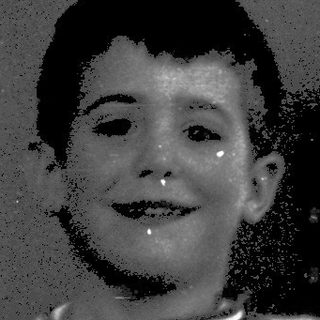 Young boy smiling indoors with suspenders.