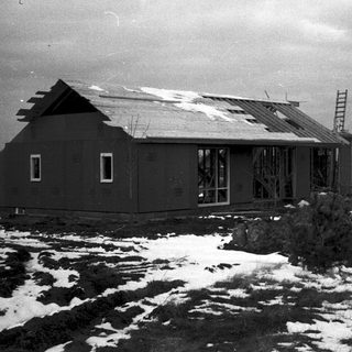 Abandoned, snow-covered single-story building in rural setting.