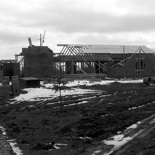 Construction site with skeletal building frame under winter conditions.