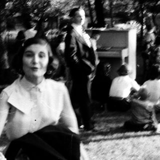 People dancing outdoors in mid-20th-century attire.