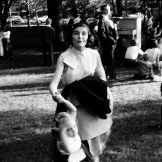People dancing outdoors in mid-20th-century attire.