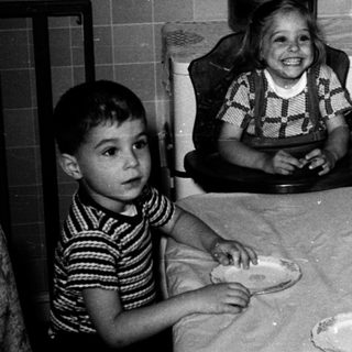 Four children celebrating a birthday with cake indoors.