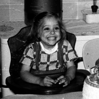 Four children celebrating a birthday with cake indoors.