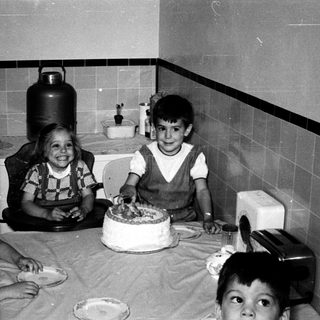 Four children celebrating a birthday with cake indoors.