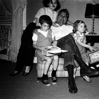 Family posing indoors with vintage luggage and books.