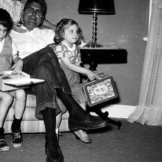 Family posing indoors with vintage luggage and books.