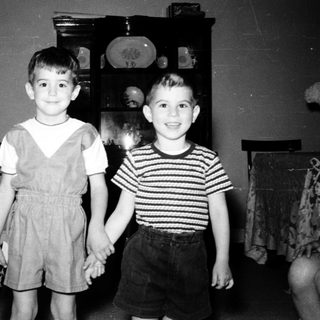Two young boys posing indoors in 1950s-style clothing.