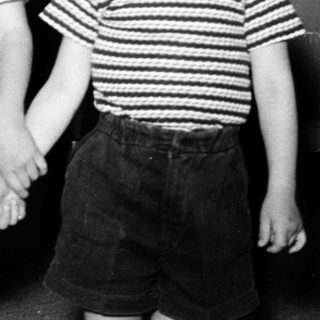 Two young boys posing indoors in 1950s-style clothing.