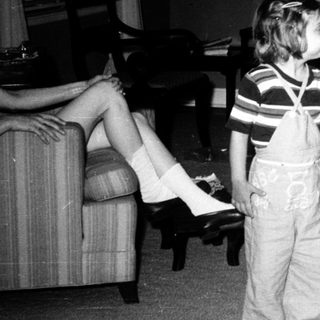 Two children playing indoors with adult supervising.